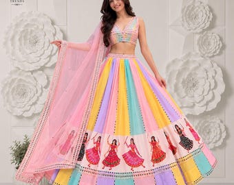 Puede incluir: Un conjunto de lehenga choli multicolor que presenta una blusa sin mangas con cuello en V con adornos reflectantes y una falda voluminosa con paneles verticales de color rosa, amarillo y azul, decorada con figuras impresas y un dupatta rosa a juego.