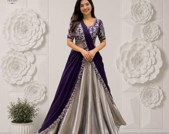 Puede incluir: Un vestido largo hasta el suelo con un corpiño de color morado intenso con bordados plateados y mangas cortas, combinado con una falda fluida de color plata metalizada. Incluye una capa drapeada morada con borde floral plateado.