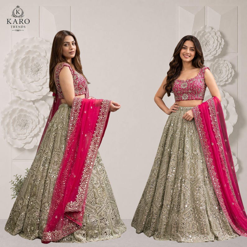 May include: A two-piece lehenga set featuring a sleeveless fuchsia pink blouse with intricate embroidery and a floor-length beige skirt heavily embellished with silver sequins, mirrors, and embroidery, paired with a matching fuchsia pink dupatta.