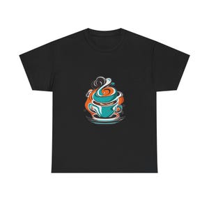 May include: A black short-sleeve t-shirt featuring a central graphic of a stylized teal coffee cup on a saucer. The design includes swirling orange and white steam rising from the cup, with dark outlines and abstract shapes surrounding the mug.