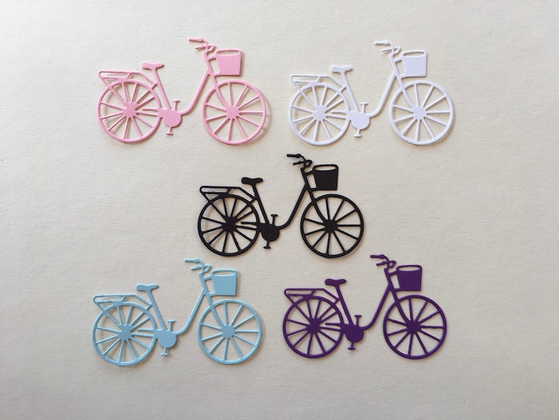 Puede incluir: Cinco recortes de papel de bicicletas con cestas. Las bicicletas son de color rosa, blanco, negro, azul claro y morado.