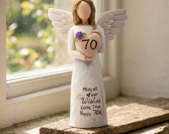 May include: A standing angel figurine with light brown hair and white wings, wearing a long white gown. The angel holds a heart-shaped object marked with the number 70. The gown features the text: May all your Wishes Come True Happy 70th.