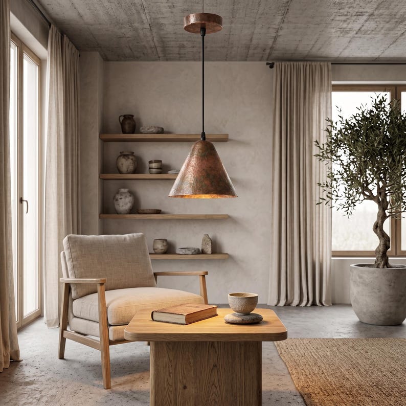 May include: A conical pendant light fixture with a textured, hammered copper finish suspended by a black cord from a matching circular copper ceiling canopy. The lamp features a wide opening at the bottom, revealing a warm, reflective interior surface.