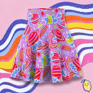 May include: A lavender skater skirt featuring a repeating pattern of red and pink planets with rings, yellow crescent moons with faces, blue clouds, and small red and lime green stars. The skirt has a high waistband and a flared, pleated silhouette.