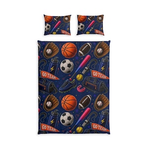 Op de afbeelding: Een beddengoedset met een donkerblauw dekbedovertrek en twee vierkante kussenslopen met een herhalend sportpatroon. Het ontwerp bevat basketballen, voetballen, honkballen, handschoenen, knuppels, waterflessen, fluitjes en GO TEAM wimpels.