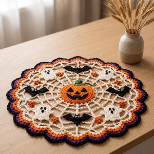 May include: A round, crocheted doily featuring a central orange jack-o'-lantern surrounded by a web pattern. The design includes white ghosts, black bats, and small orange stars, finished with a scalloped border in orange, purple, and black.