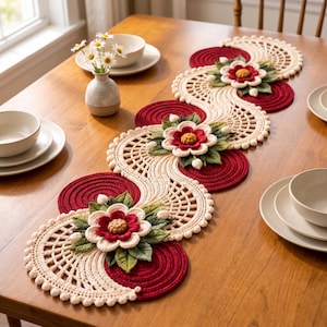 May include: A long, crocheted table runner featuring a wavy design of cream-coloured lattice patterns and solid deep red circular motifs. The runner is decorated with three-dimensional floral appliqués in red, cream, and green leaf accents.