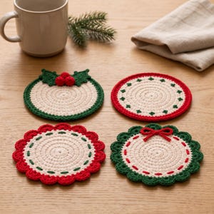 Puede incluir: Cuatro posavasos redondos de ganchillo con motivos navideños. Uno tiene hojas de acebo verdes y bayas rojas, otro un borde rojo con detalles verdes, otro un borde festoneado rojo y otro un borde festoneado verde con un lazo rojo.
