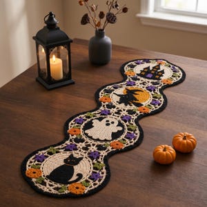 May include: A scalloped crochet table runner featuring four circular motifs with Halloween designs: a black cat, a white ghost, a witch on a broomstick, and a haunted house, accented with orange pumpkins, purple stars, and green leaves.