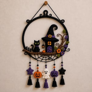 Può includere: Una decorazione da parete circolare all'uncinetto nera con un gatto nero, una casa a forma di cappello da strega e una ragnatela. Sotto, cinque ornamenti pendenti includono stelle viola, zucche arancioni e viola e un fantasma bianco.