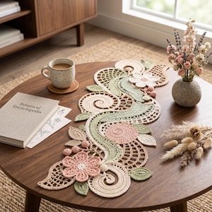 May include: A decorative crochet table runner featuring an intricate design of swirling patterns, leaves, and flowers in soft shades of cream, sage green, and dusty pink. The runner is crafted with varied stitch textures and openwork details.