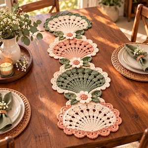 Può includere: Un lungo runner da tavola rettangolare all'uncinetto con un motivo ripetuto a ventaglio nei colori crema, verde salvia e rosa antico. Il design include fiori tridimensionali all'uncinetto con centri testurizzati e foglie tra le sezioni.