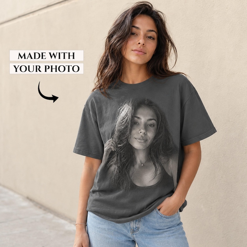 May include: A charcoal gray short-sleeve t-shirt featuring a large black and white photographic print of a person on the front. Above the print, the text reads MADE WITH YOUR PHOTO with a black arrow pointing down toward the image.