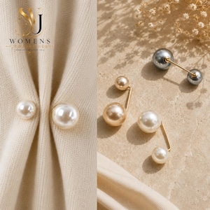 May include: A set of double-sided pearl pins featuring spherical white, cream, and grey pearls attached to thin gold-toned metal bars. The pins are shown both securing a beige fabric and displayed separately on a textured surface.