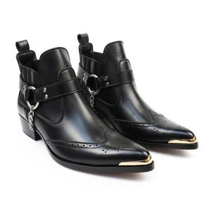 Puede incluir: Un par de botines de cuero negro con punta afilada y puntera de metal dorado, detalles brogue y una correa decorativa en el tobillo con un anillo de metal plateado y una cadena corta colgante en el lado exterior de cada bota.