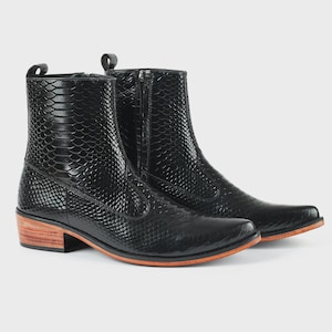 May include: A pair of black ankle boots featuring a textured snakeskin pattern, a side zip closure, and a stacked wooden heel with a natural light brown finish. The boots have a pointed toe design and a smooth black outsole.