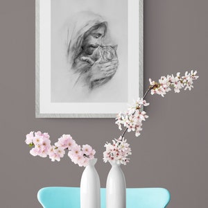 May include: A black and white pencil drawing of a person holding a cat. The person is wearing a hooded robe and has a beard. The cat is looking up at the person.