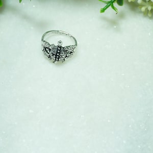 May include: A silver-toned metal ring featuring a central turtle motif with intricate engraved detailing on the shell and flippers. The band is thin and circular, showcasing a polished finish with darkened recessed areas to highlight the design.