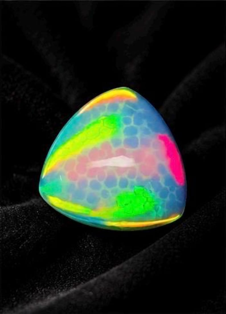 May include: A triangular cabochon gemstone featuring a translucent, milky white base with a distinct honeycomb pattern. The surface displays vibrant, iridescent flashes of neon green, bright yellow, and hot pink across its smooth, domed top.