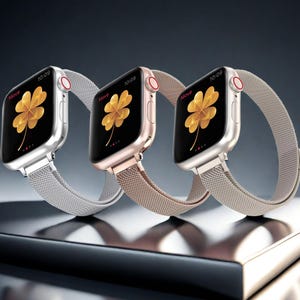 May include: Three smartwatches with rectangular screens displaying a golden four-leaf clover graphic and the text Move and 10:09. The watches feature metallic mesh bands in silver, rose gold, and gold, each with a red-accented digital crown.
