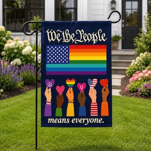 Może przedstawiać: Ciemnoniebieska flaga ogrodowa z napisem We the People na górze i means everyone. na dole. W centrum znajduje się flaga z niebieskim polem z białymi gwiazdami i tęczowymi pasami. Poniżej sześć dłoni trzyma różne symbole serc.