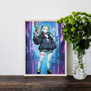 Peut inclure: Une impression d'art encadr&eacute;e repr&eacute;sentant un personnage aux cheveux clairs avec des couettes, portant une veste sombre surdimensionn&eacute;e et tenant un pistolet futuriste rose. Le fond montre une rue urbaine n&eacute;on aux tons violets et bleus.
