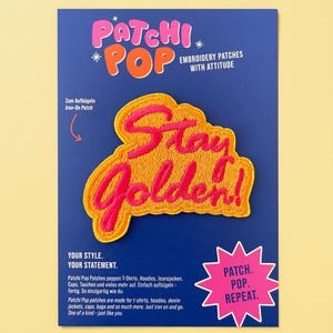 Könnte beinhalten: Ein Aufbügel-Stickaufnäher auf einer blauen Präsentationskarte. Der Aufnäher zeigt den Schriftzug Stay Golden! in leuchtend pinker Schreibschrift mit gelbem Rand. Die Karte enthält den Text Patchi Pop, Embroidery Patches With Attitude und Patch. Pop. Repeat.