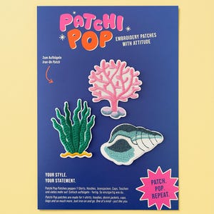 Op de afbeelding: Een blauwe displaykaart met drie geborduurde strijkpatches: een roze koraalrif, een groene zeewierplant en een blauw-witte schelp. De kaart bevat de tekst Patchi Pop, Embroidery Patches With Attitude en Patch. Pop. Repeat.