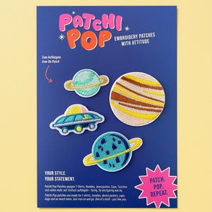 Puede incluir: Una tarjeta de presentación azul con cuatro parches bordados de temática espacial: un planeta turquesa con anillo dorado, un planeta grande con rayas beige y marrones, un OVNI azul y un planeta azul con anillo amarillo. Incluye el texto PATCHI POP.