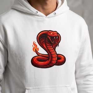 May include: A white hooded sweatshirt featuring a graphic print of a red cobra snake with glowing eyes and an open mouth. The snake has a flame-like tail and is coiled in a central position on the chest of the garment, which includes a hood.
