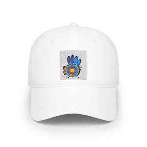 May include: A white baseball cap featuring a centred rectangular patch. The patch displays a stylised graphic with concentric circles in yellow, orange, and blue, topped with blue petal-like shapes and accented by small orange and black dots.
