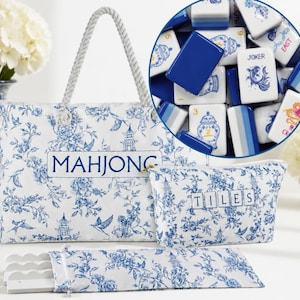 May include: A white tote bag, a matching zippered pouch labeled TILES, and a long rectangular case, all featuring a blue floral pattern with pagodas and birds. The tote is labeled MAHJONG. A circular inset shows blue and white mahjong tiles.