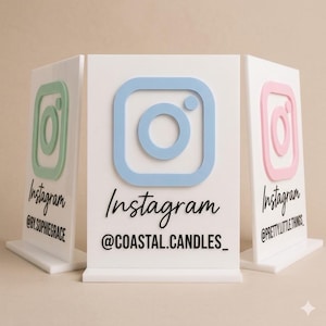 Może przedstawiać: Trzy białe, prostokątne tabliczki akrylowe ze stojakami. Każda tabliczka posiada wypukłe logo Instagrama w kolorze pastelowej zieleni, jasnego błękitu lub różu. Czarny tekst zawiera napis Instagram oraz nazwy użytkowników @BY.SOPHIEGRACE, @COASTAL.CANDLES_ i @PRETTY.LITTLE.THINGS.
