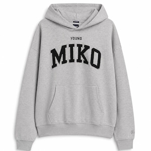 May include: A heather gray long-sleeve hooded sweatshirt featuring a front kangaroo pocket and a hood with drawstrings. The chest displays the word YOUNG in small black letters above the word MIKO in large, bold, black collegiate-style lettering.