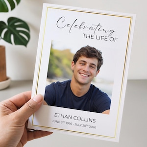 May include: A rectangular memorial card featuring a gold border, a central photograph of a smiling person in a navy blue shirt, and the text Celebrating THE LIFE OF ETHAN COLLINS JUNE 3RD 1995 - JULY 20TH 2026 printed in black on a white background.