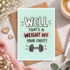 Può includere: Un biglietto d'auguri rettangolare con sfondo verde menta chiaro che presenta il testo nero WELL THAT'S A WEIGHT OFF YOUR CHEST! e un'illustrazione di un manubrio grigio. Il biglietto è centrato su una busta marrone, circondato da fiori e una penna.