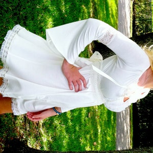 May include: A white, off-the-shoulder dress with long bell sleeves and lace trim. The dress has a fitted bodice and a flowing skirt.