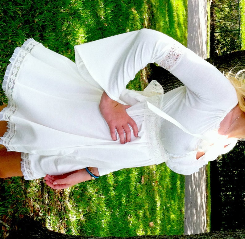 May include: A white, off-the-shoulder dress with long bell sleeves and lace trim. The dress has a fitted bodice and a flowing skirt.