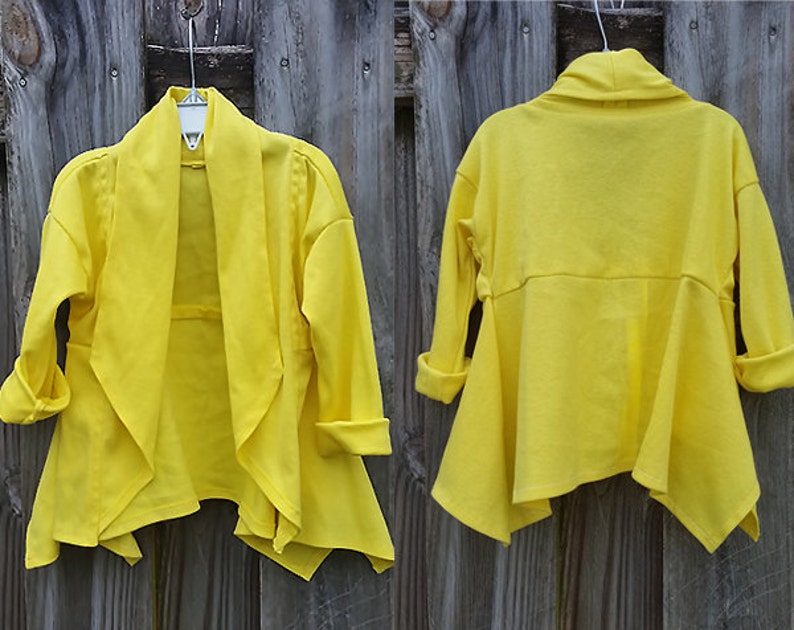 May include: A bright yellow cardigan with a draped front and long sleeves. The cardigan is made of a soft, lightweight fabric and has a relaxed fit.