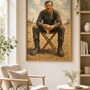 May include: A framed wall art print depicting a person sitting on a wooden folding stool in a dusty, barren landscape. The person wears dark, textured clothing and lace-up boots, holding a pipe in their mouth and a white cloth in their hands.