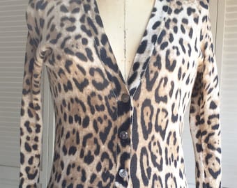 May include: A long-sleeved cardigan with a leopard print pattern. The cardigan has a V-neck and a button-up front.