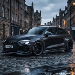 以下が含まれることがあります： マットダークグレーのAudiハッチバック。ワイドボディキット、黒いマルチスポークホイール、174 AUKと書かれたフロントナンバープレートが特徴。濡れた石畳の通りに駐車されており、周囲には背の高い歴史的な石造りの建物が立ち並んでいる。