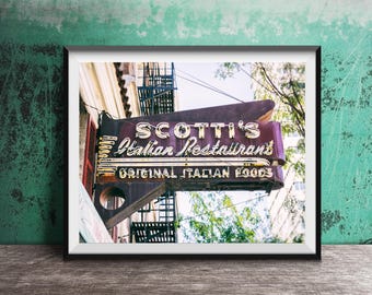 May include: A vintage neon sign for Scotti's Italian Restaurant, with the words "Original Italian Foods" underneath. The sign is mounted on a building with a fire escape in the background.