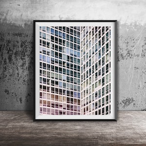 Puede incluir: Una fotografía enmarcada de un edificio moderno con una cuadrícula de ventanas. Las ventanas son una mezcla de blanco, azul y gris. El edificio está en un entorno urbano.