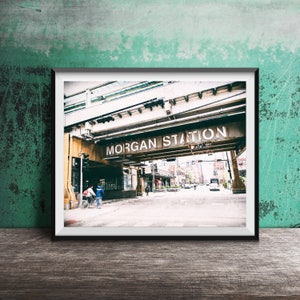 May include: A vintage-style photograph of a city street with a sign that reads "MORGAN STATION" above the street. The sign is attached to a large, metal structure that appears to be a train overpass. The photo is taken from a low angle, looking up at the sign.
