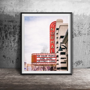 May include: A vintage movie theater marquee with red and white stripes and the words "NORMAL" in large letters. The marquee is advertising the movies "The Color Purple", "Home Alone", and "Christmas Carol".