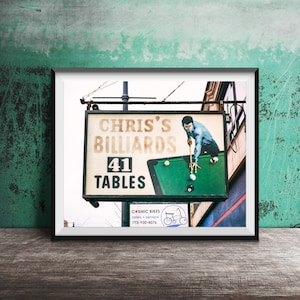 May include: A vintage sign for Chris's Billiards with a green felt pool table and a man playing pool. The sign says "Chris's Billiards 41 Tables".