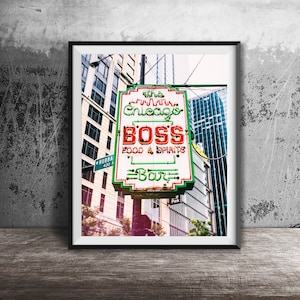 May include: A neon sign for a bar called "The Chicago Boss" with the words "Food & Spirits" and "Bar" on it. The sign is green, red, and white and is hanging from a pole in front of a building.