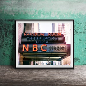 May include: A framed photograph of a building with a neon sign that reads "Rainbow Room Observation Deck NBC Studios".