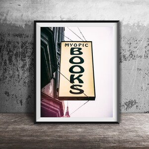 May include: A black framed photograph of a yellow sign with the text "MYOPIC BOOKS" hanging from a building.